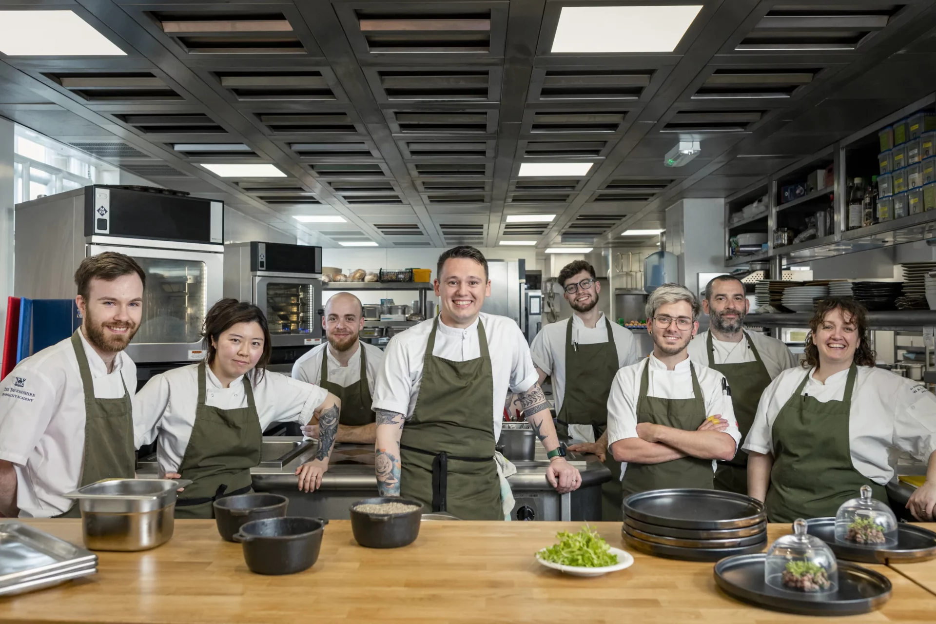 8 chefs smiling in a kitchen