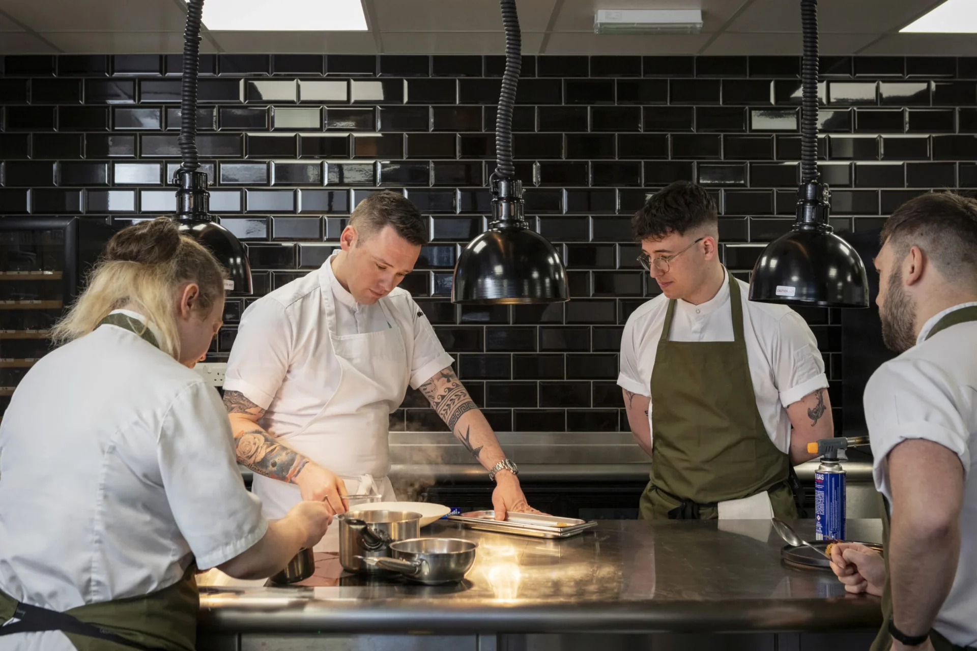 4 chefs gathered around plating a dish