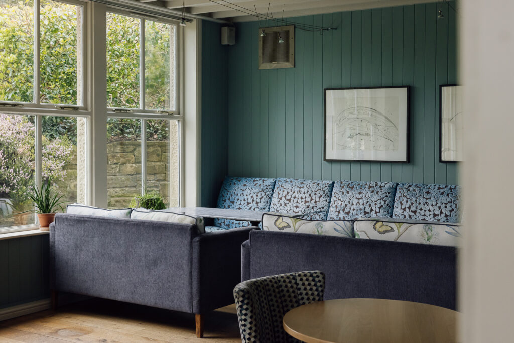Large white sash windows letting in natural light over blue bunker seating.