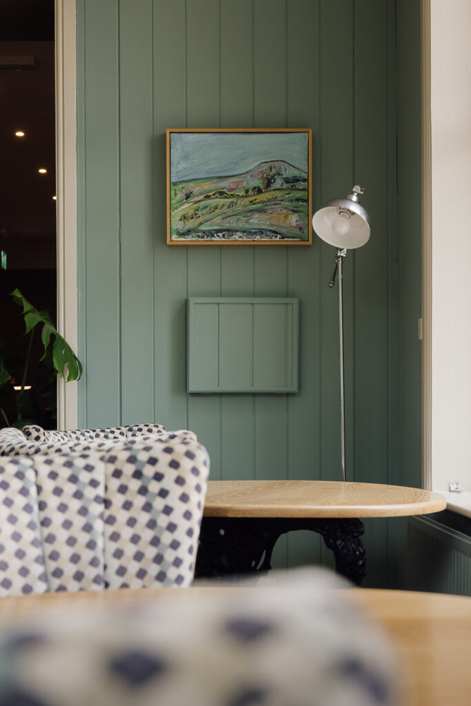 Two wooden seat tables with checked seats placed in front of large windows letting in natural light