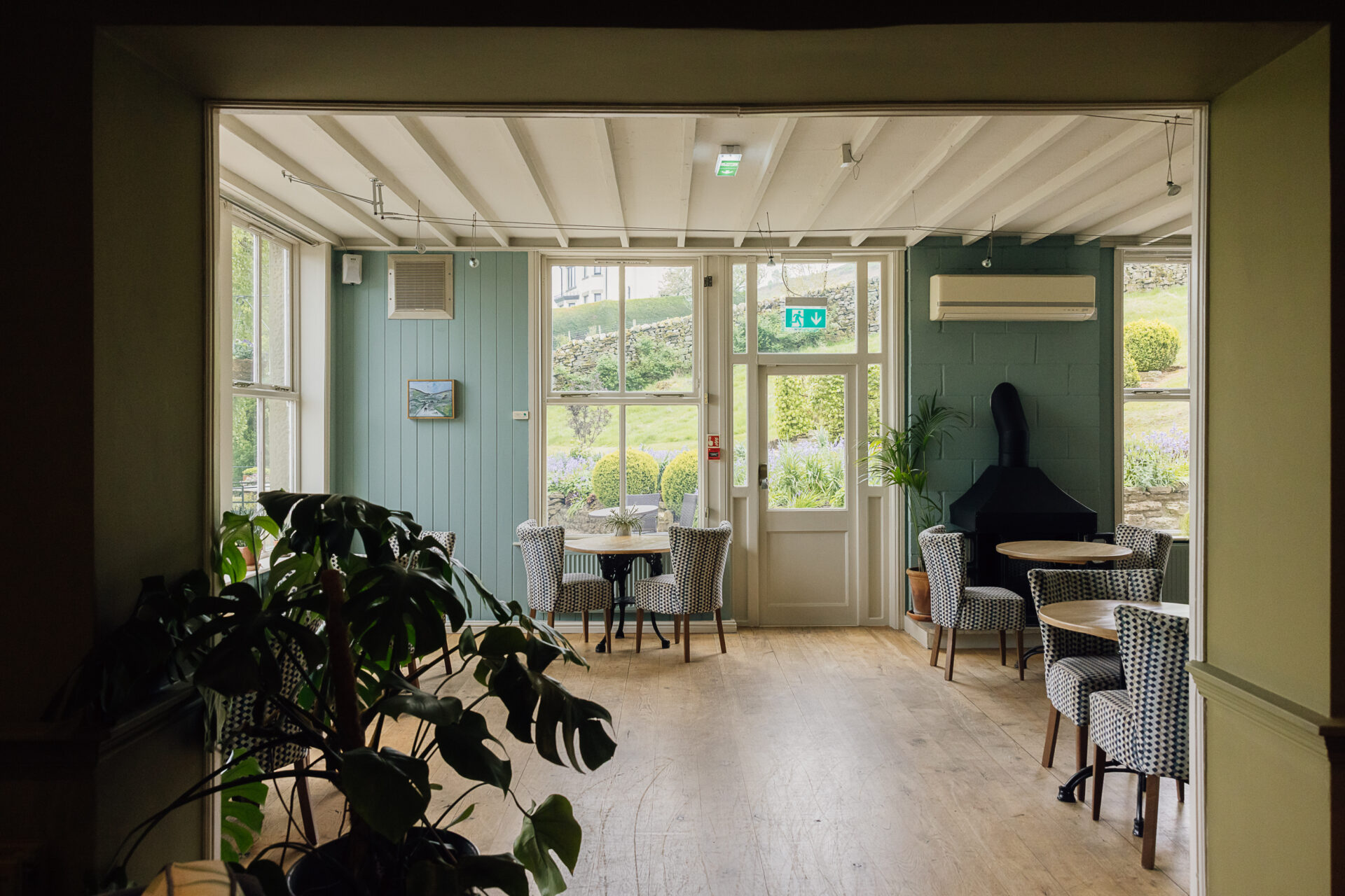 Large white sash windows letting in natural light over wooden tables set for dinner.