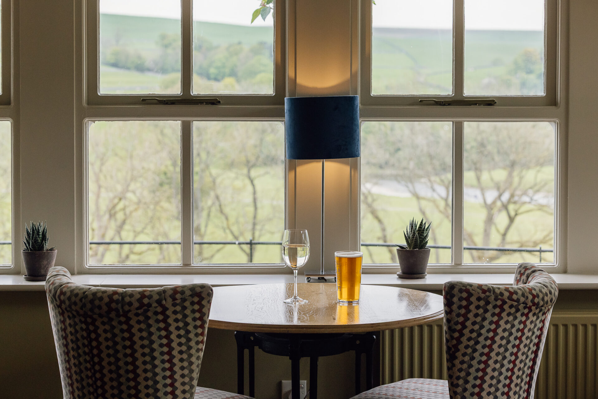 Conservatory dining room at The Fell Hotel near Bolton Abbey, featuring large windows, wooden floors, and views across the Yorkshire Dales valley.