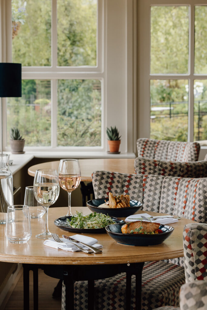 A selection of summer main courses on a table with two large glasses of wine to enjoy them with.