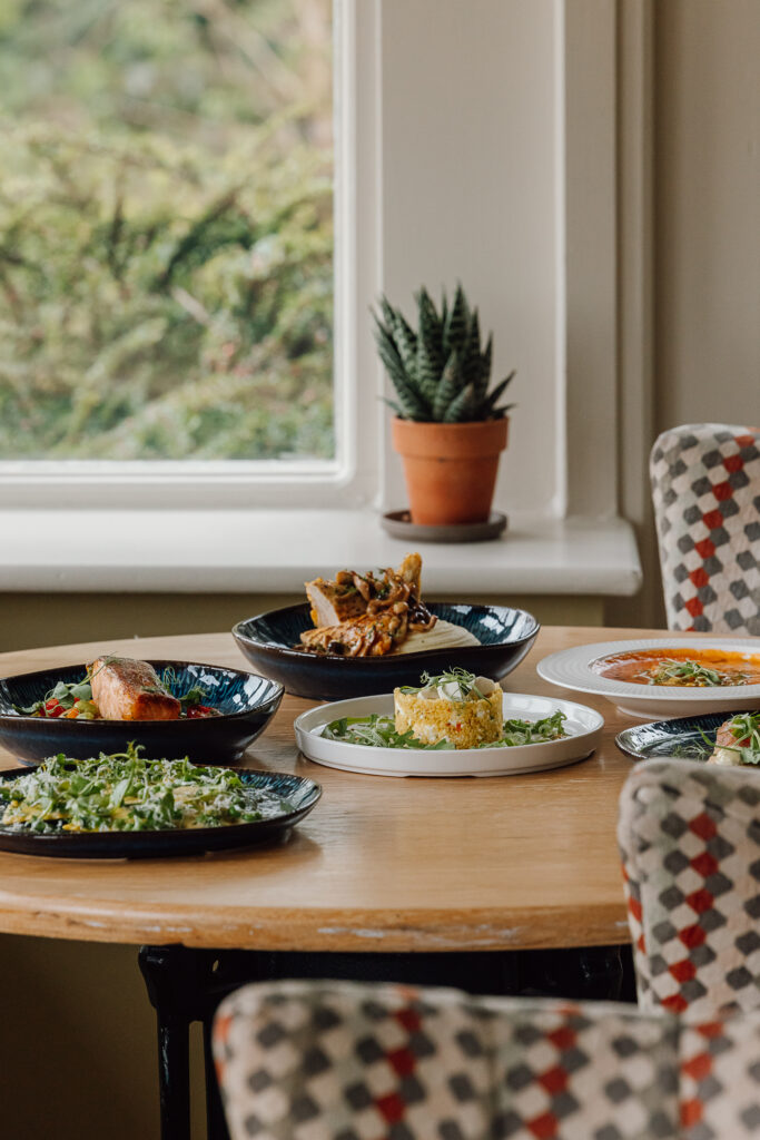 A selection of summer dishes placed on a wooden table with checked chairs