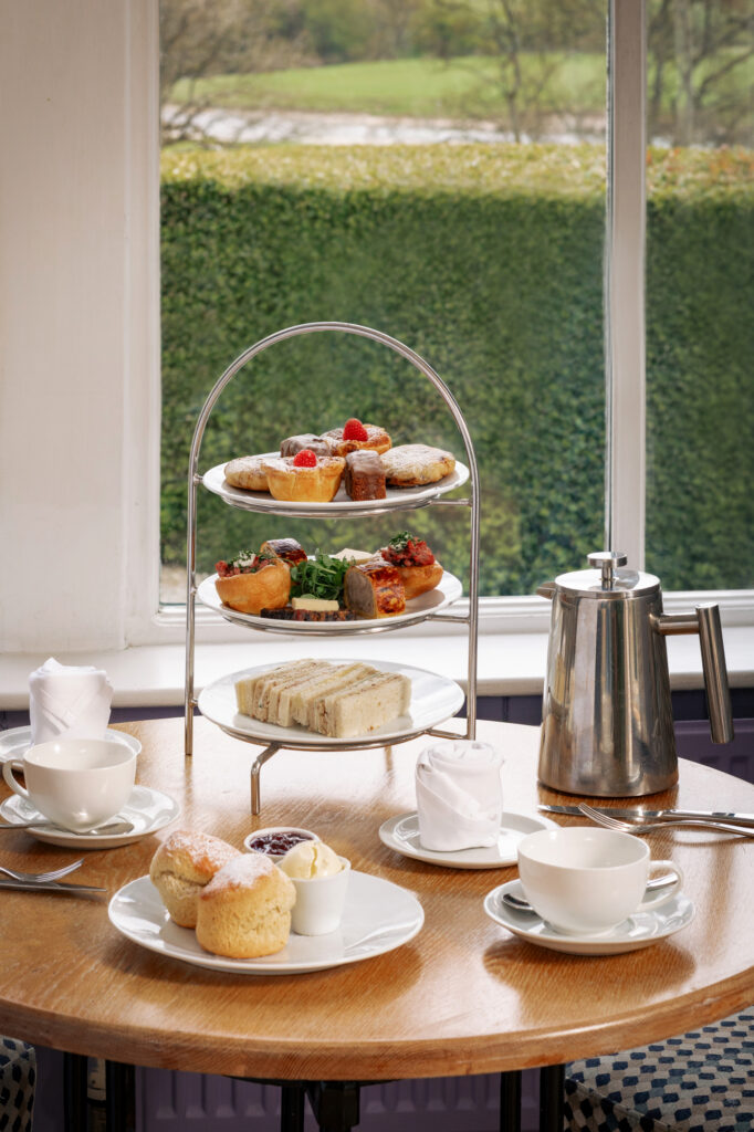 An afternoon tea stand at The Fell Hotel filled with sandwiches, sweets and scones and a side of tea.
