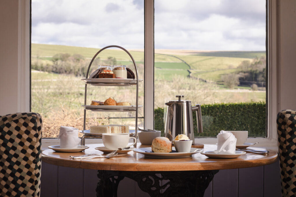 Afternoon tea is set up on a table with the rolling valley in the background.