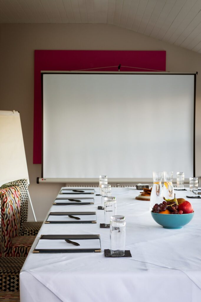 A corporate table set up with large screen and flip chart in the corner.