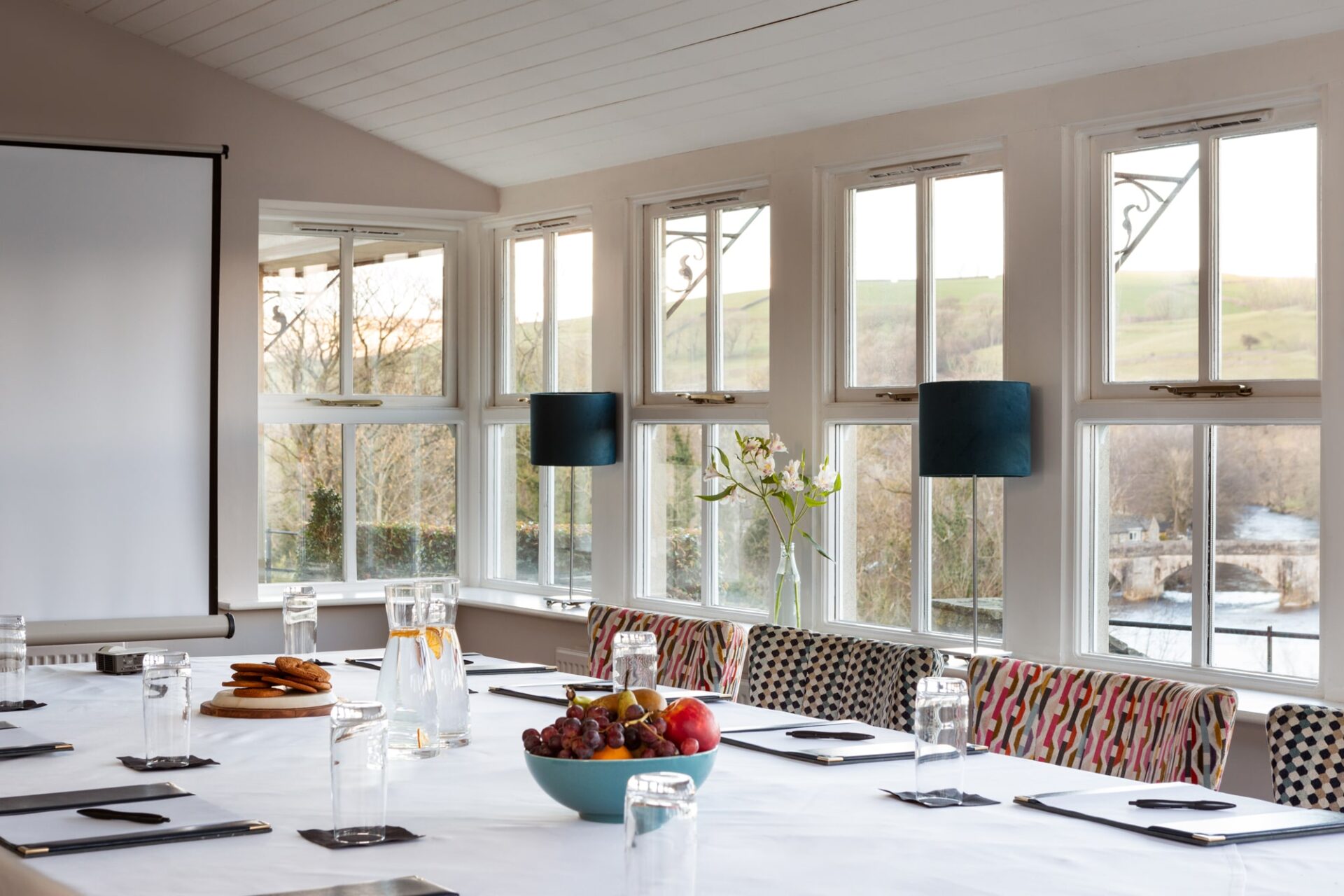 A corporate table set up with pads and pens and fruit on the table with views from the conservatory windows out to the river.