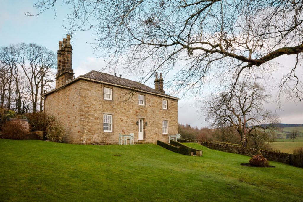 The exterior of the old farmhouse cottage with large garden with a hot tub.
