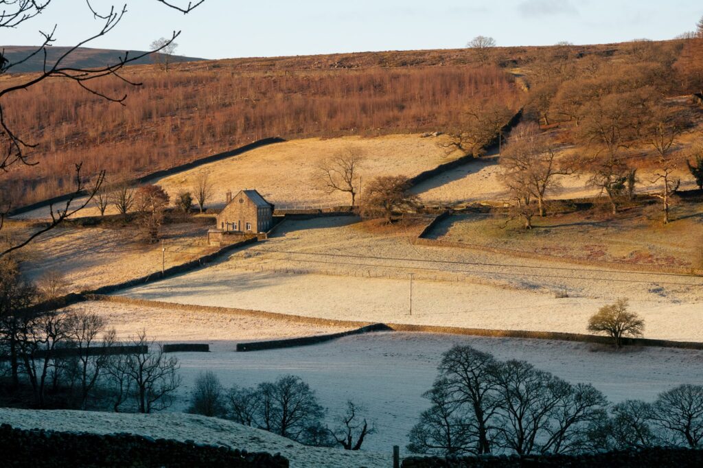 The cottage sits within the frosty hills of the Yorkshire Dales with woodland nearby.