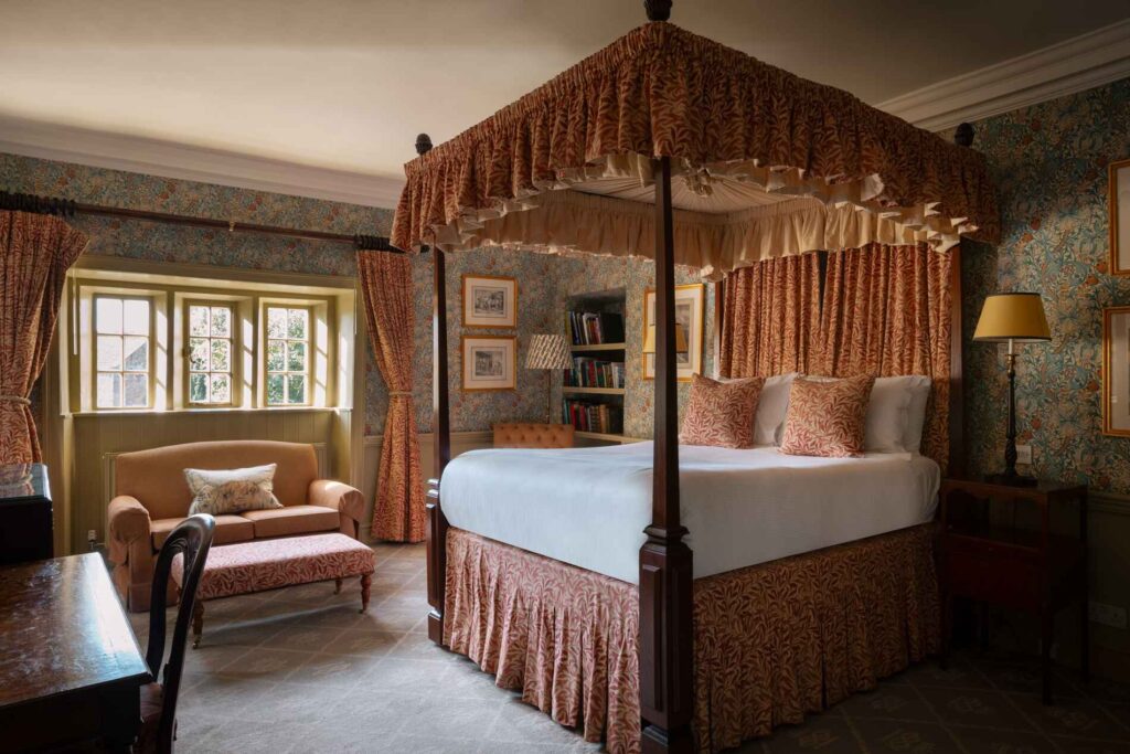 four poster bed with orange coloured soft furnishings and curtains