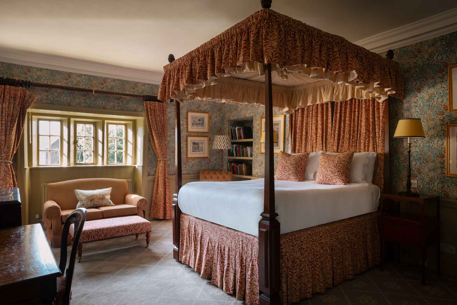 four poster bed with orange coloured soft furnishings and curtains