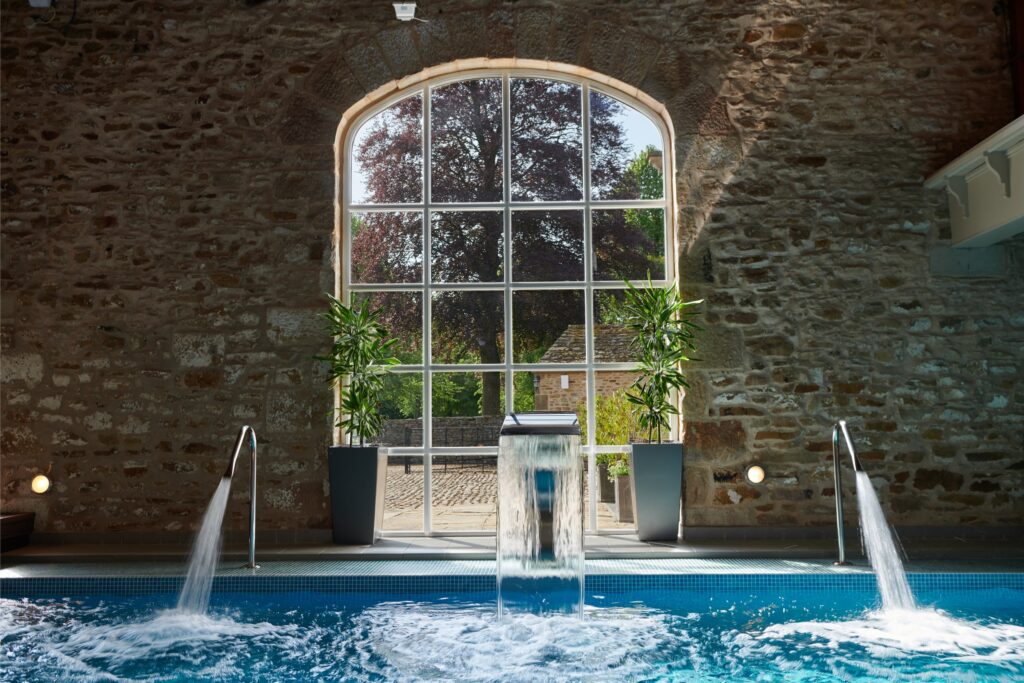 The spa pool with a large glass window looking out towards the sunshine, with the water jets on.