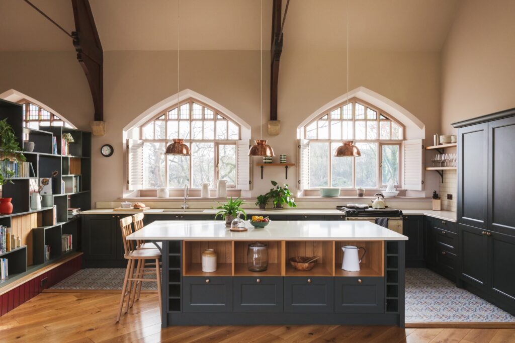 Large kitchen dining area, with island countertop and large chapel windows looking out towards the view.