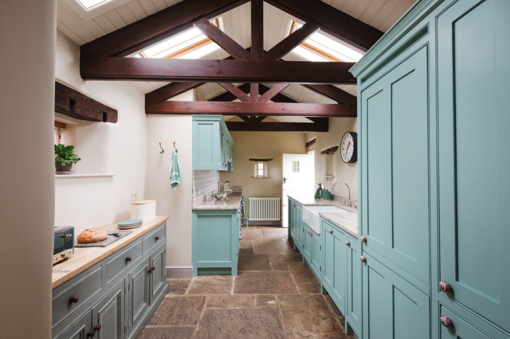 Traditional farmhouse kitchen with blue cupboard doors and beams on the ceiling.