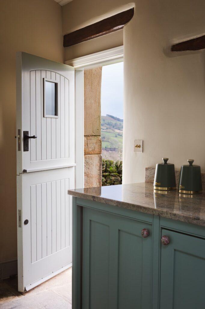 Open door in the kitchen leading out towards the garden, corner of the farmhouse style doors.
