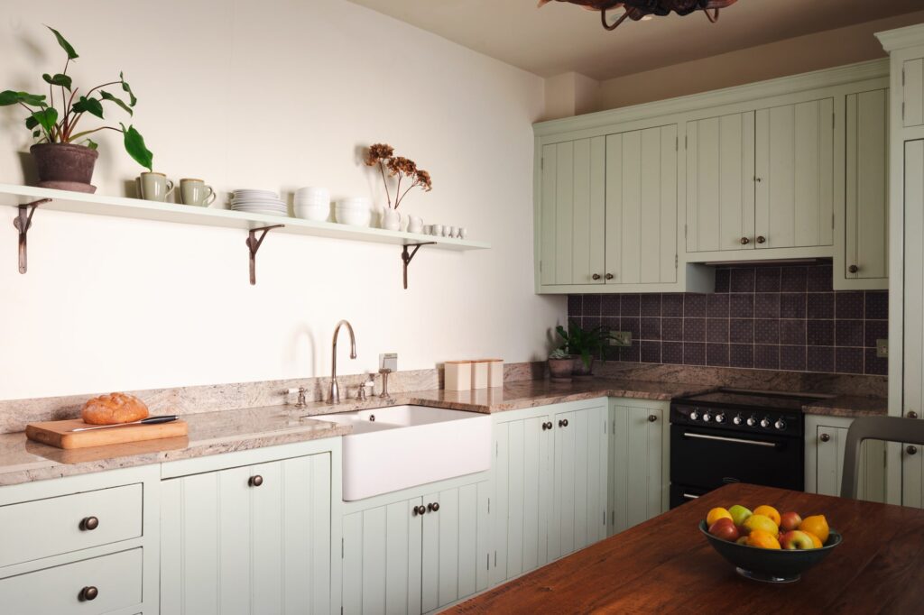 Traditional farmhouse kitchen with oak table and fruit bowl.