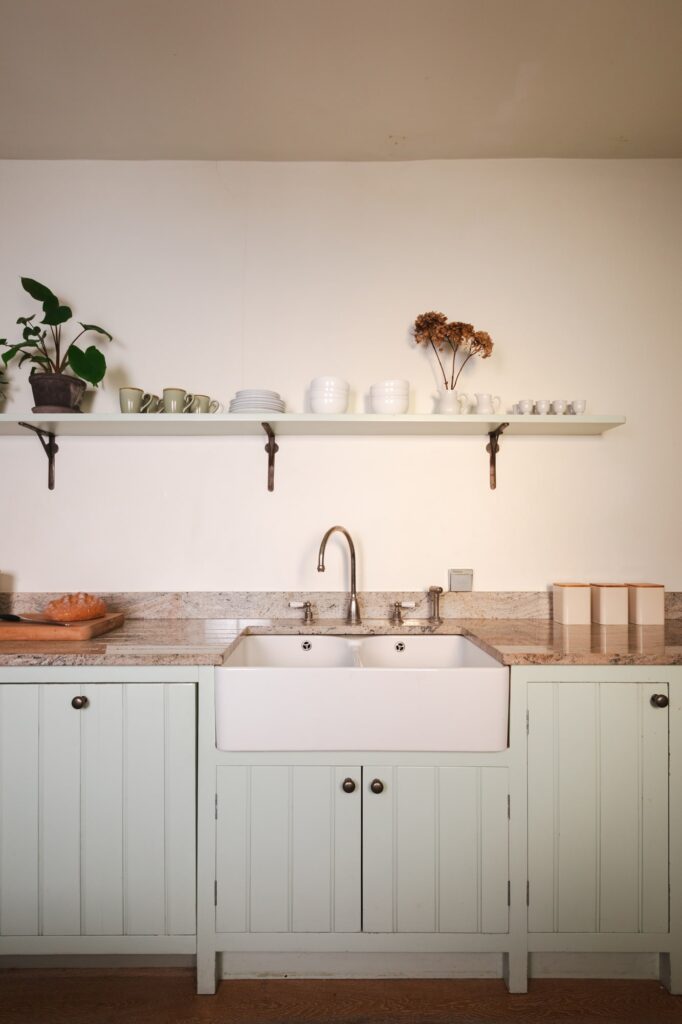 Traditional farmhouse kitchen with green cupboard doors and kitchen sink.
