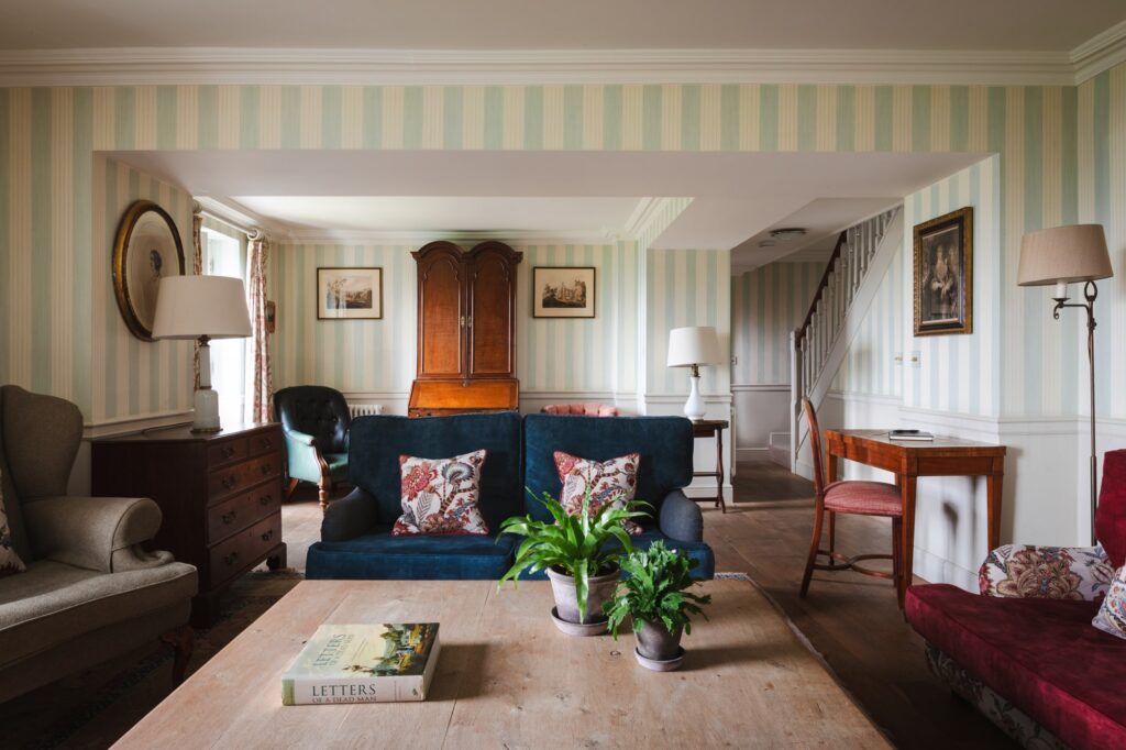 Striped wallpaper in the large living room, with stairs leading up to the bedrooms.