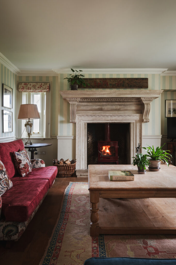 The roaring fireplace in the living room, with antique sofa and striped wallpaper.