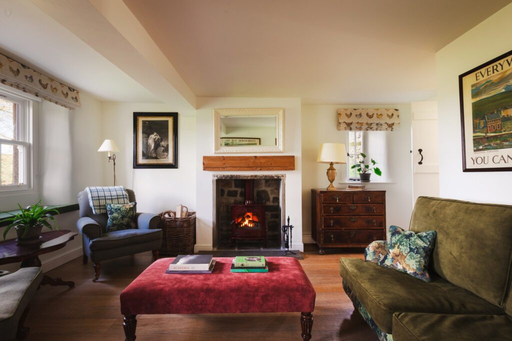 Large living room with antique furnishings and artwork, and roaring open fire.