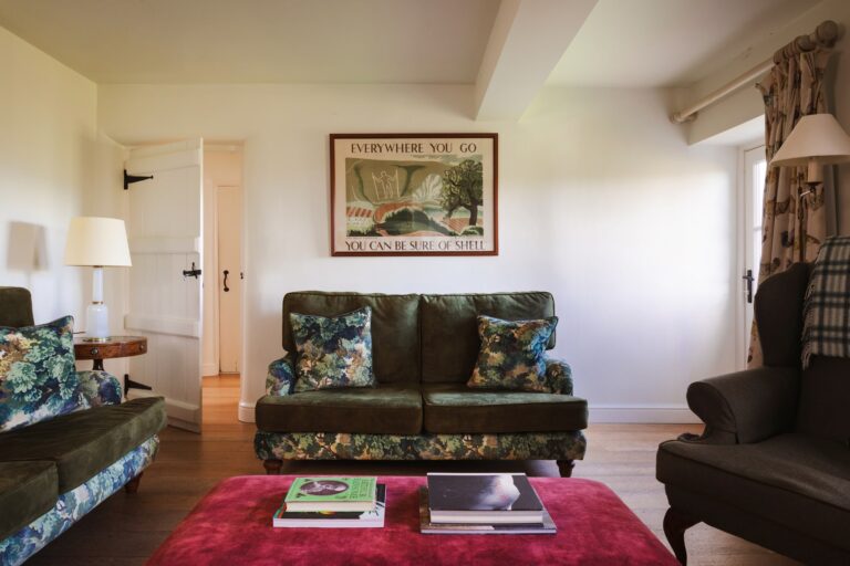 Antique furniture in a living room, green floral sofas and artwork on the walls.