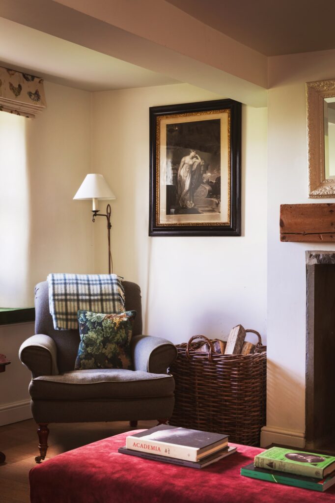 Armchair in the corner of the living room with checked throw and antique furnishings surrounding it.