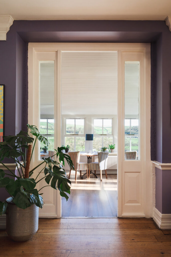 The entrance to the conservatory with large windows and rolling views of the hills.