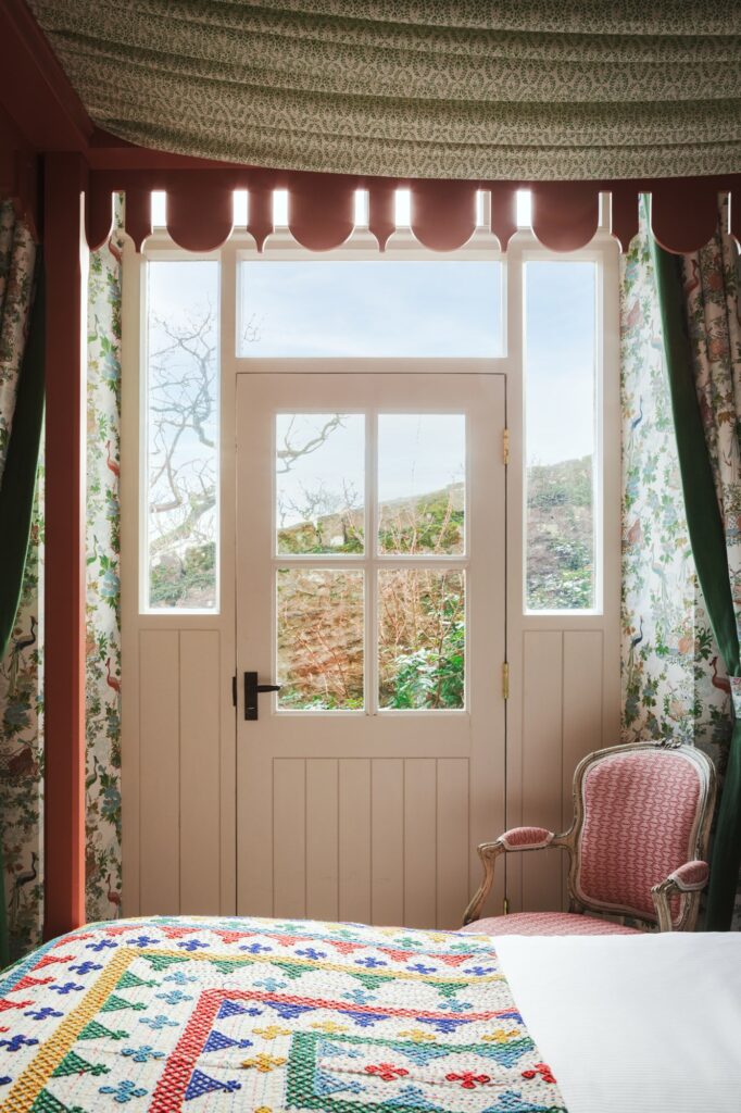 A door in the room leading out towards the garden, within the canopy of the four-poster bed.