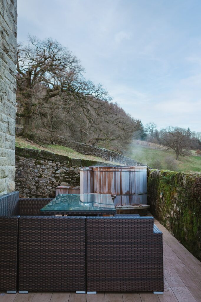 The patio space with outdoor furniture and steaming hot tub in the background.
