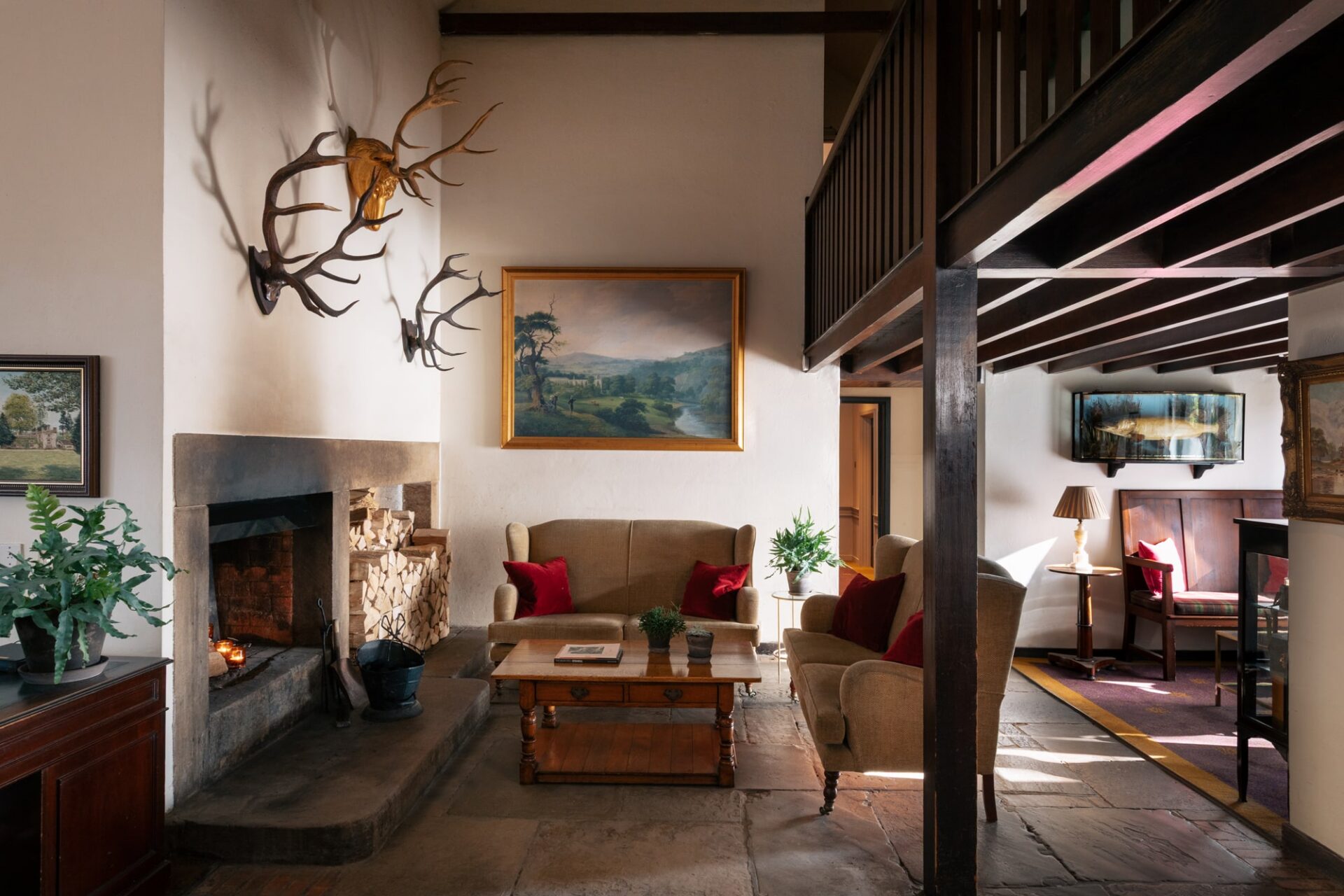 Reception area with burning fire, stacked logs in the corner and seating.