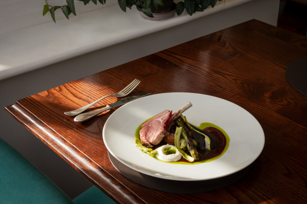 A table of food on a dark wood table with green chair.