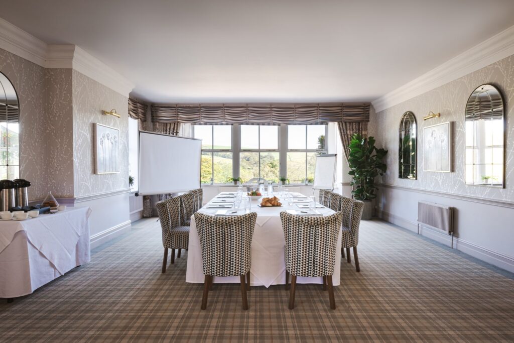 A large open room with corporate table in the centre with large screen in the corner.