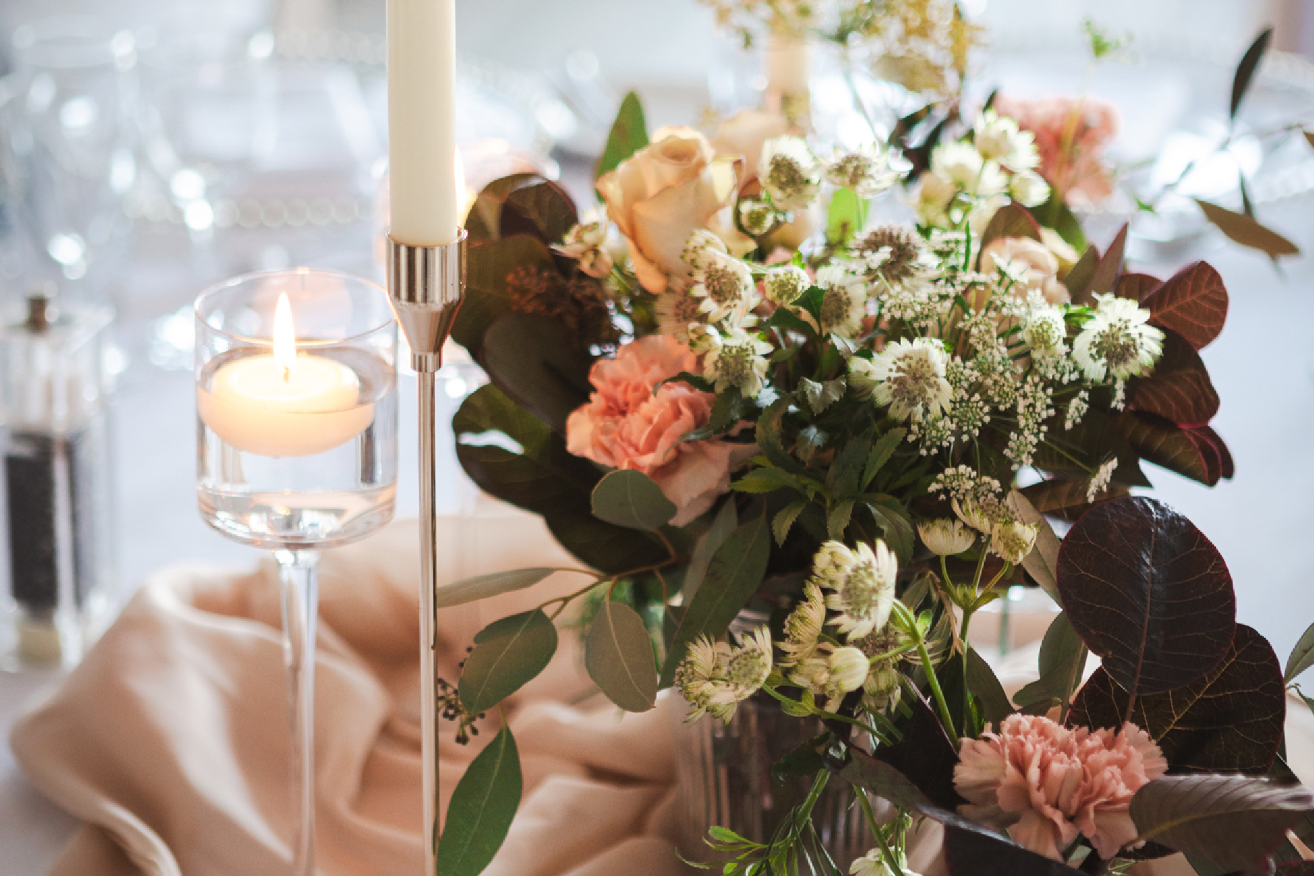 A close up picture of a wedding table with floral display and candles.