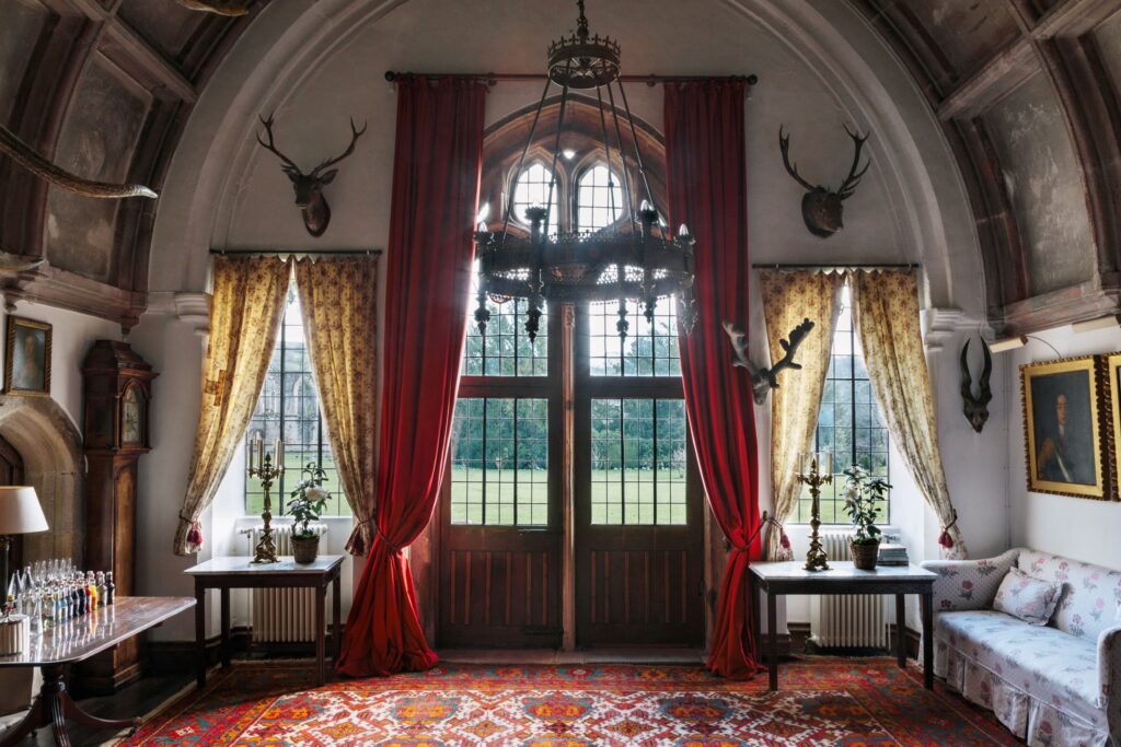 The grand entranceway to the hall with draping curtains and stags heads hanging.