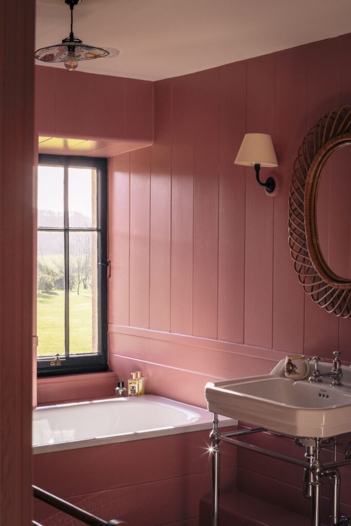 A pink bathroom with delicate furnishings and a window onto the dales.