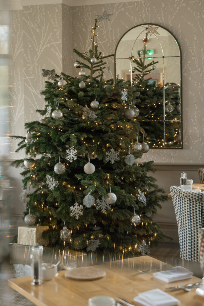 A Christmas tree with round and snowflake silver baubles