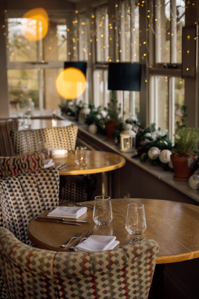 Tables set for dinner with Christmas garland laid on the windowsill in front