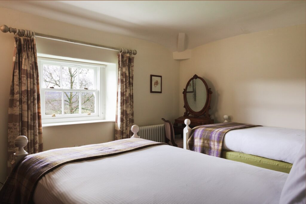 Twin bedroom with checked throws and antique furnishings.