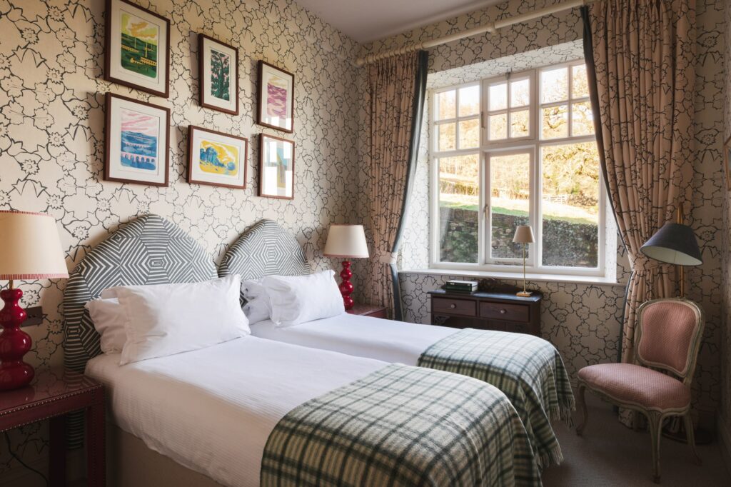 A twin bedroom with patterned wallpaper and headboards.