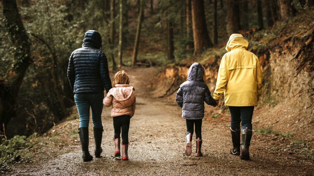 Mothers walking with their daughters in the forest rear view