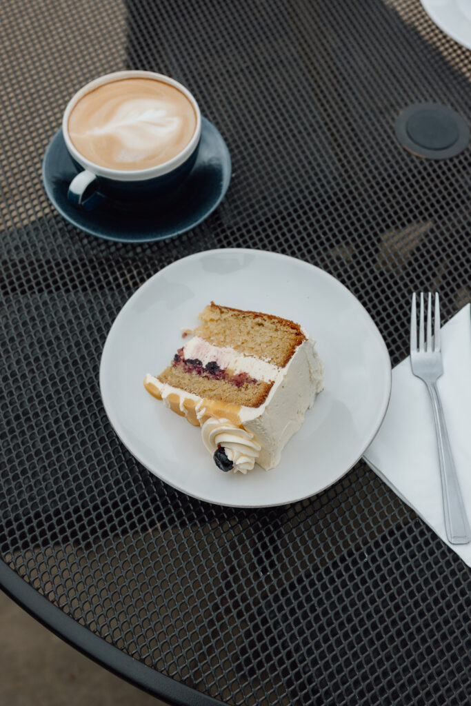 Lemon & Blueberry Cake, Carrot Cake placed on a table with a coffee.