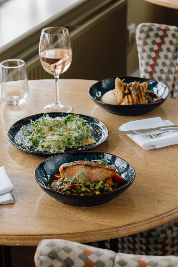 A selection of summer main courses on a table with two large glasses of wine to enjoy them with.