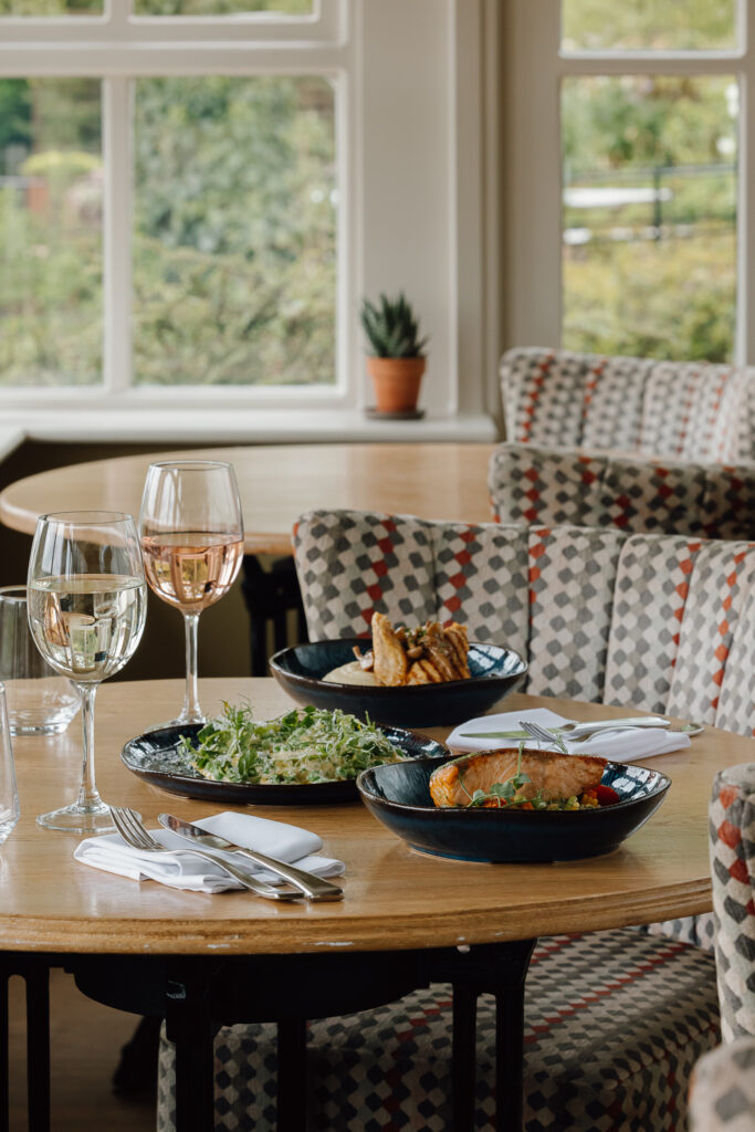 A selection of summer main courses on a table with two large glasses of wine to enjoy them with.